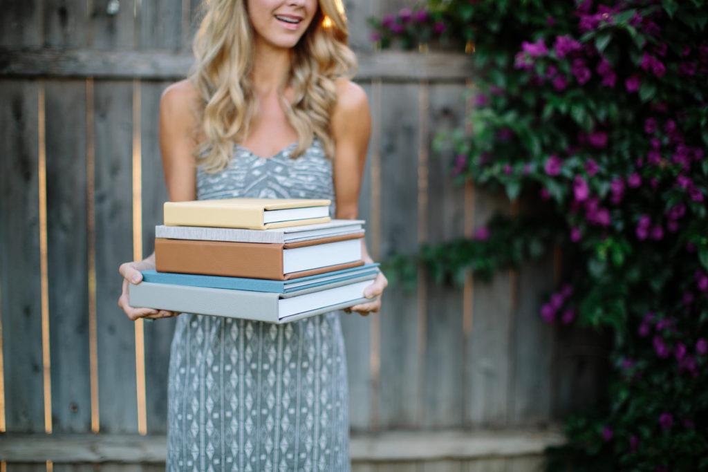 Woman holding a stack of wedding albums. 