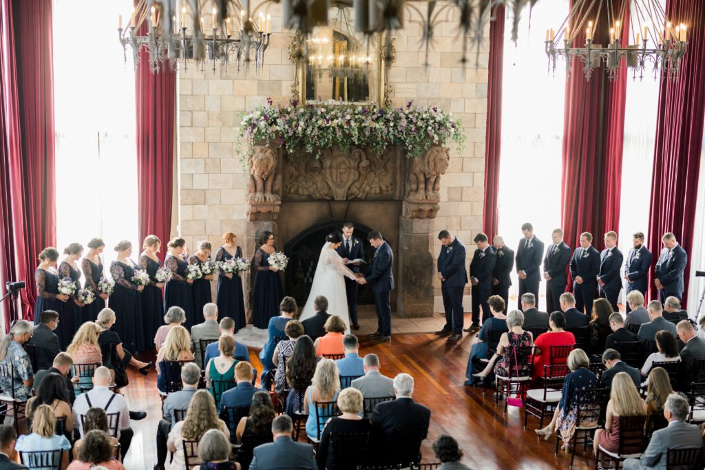 Bride and groom say prayer in front of the grand fireplace at the Dover Hall wedding venue. 