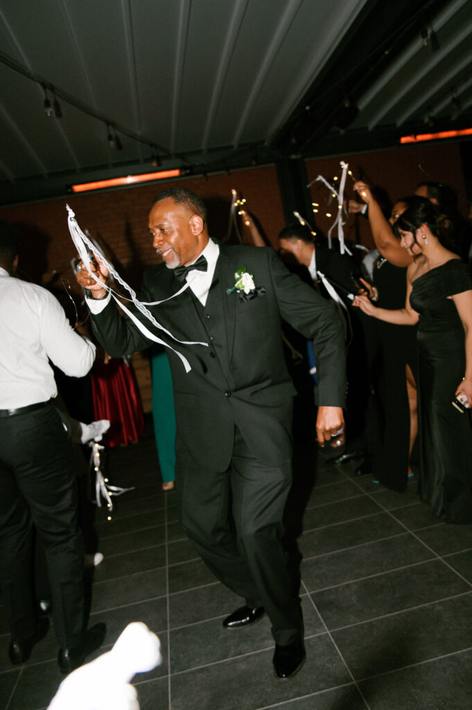 father running through a ribbon exit surrounded by cheering guests during their Common House Richmond wedding, photographed by Chelsea Schmidt Photography.