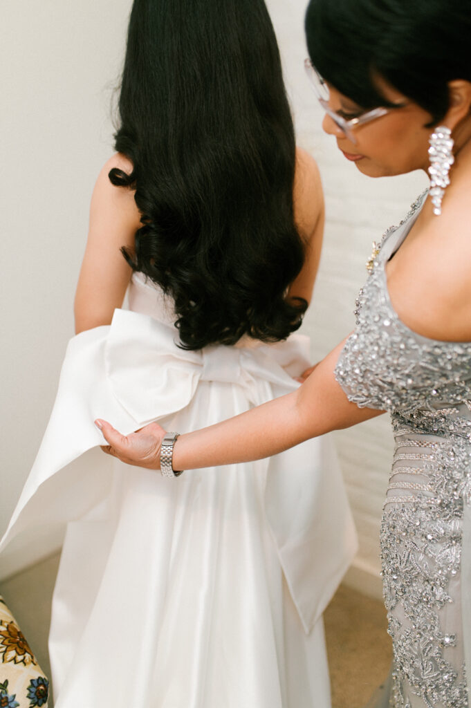 Mother of the bride fixes the bride's bow on her wedding dress
